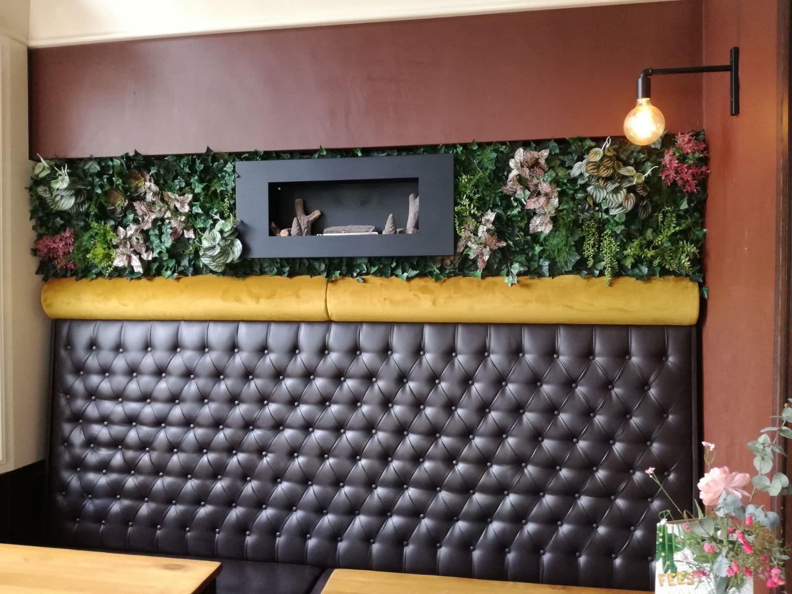 Groenwand rond een sfeerhaard in een restaurant